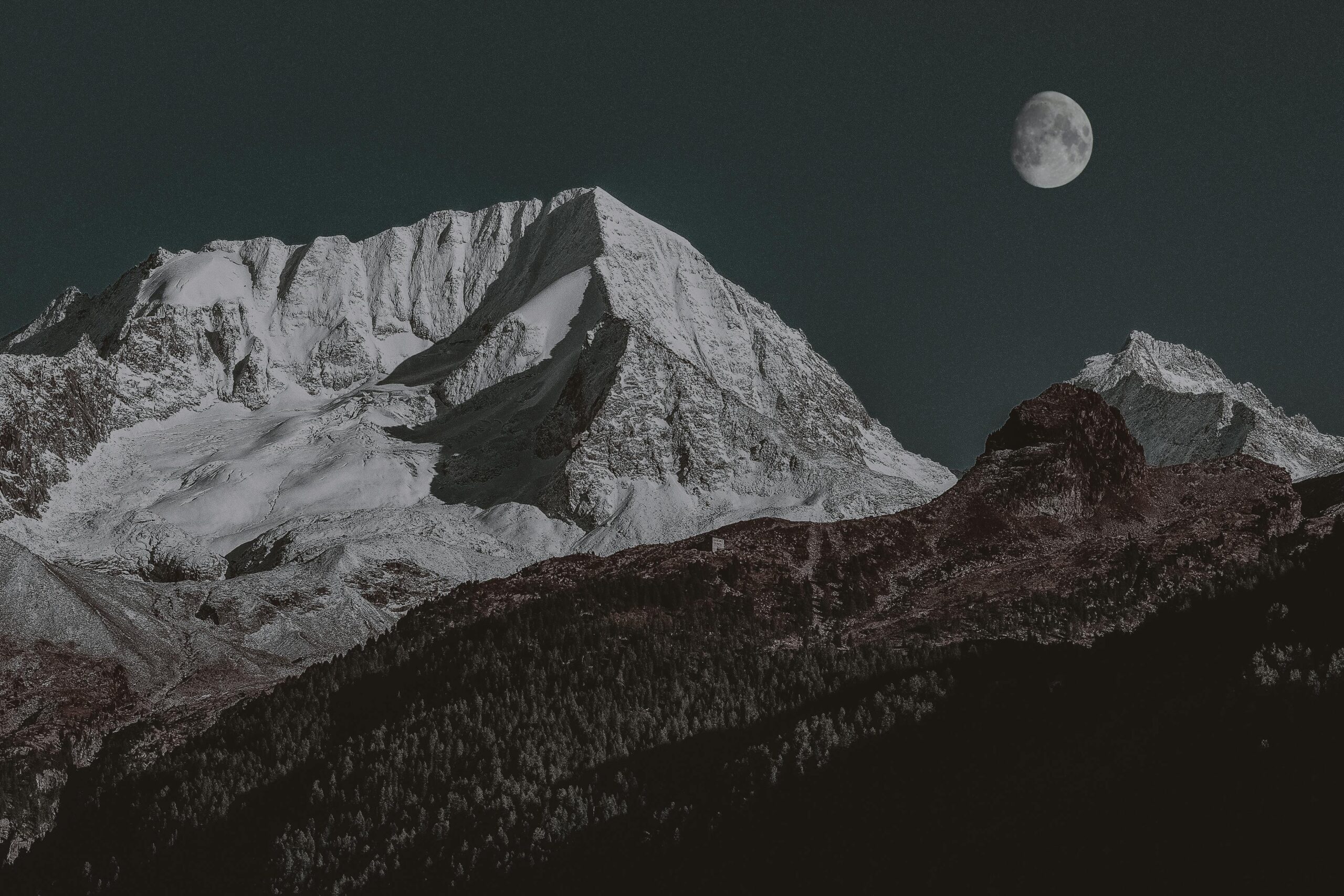 Breathtaking view of a majestic snow-capped mountain under a clear moonlit night sky.